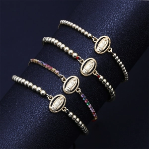 Detailed view of gold beaded religious bracelets with Mother Mary charms and zircons