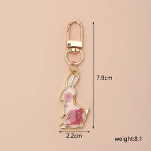 Detail of bunny resin keychain with pink dried flowers, measuring 7.9cm by 2.2cm