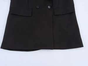 Detail of black double-breasted blazer showing front flap pockets and smooth fabric