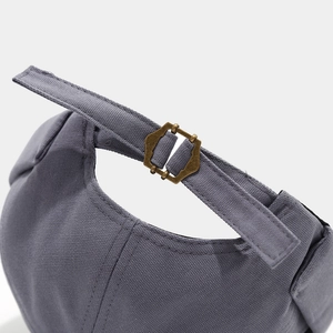 Detailed macro view of the bronze metal buckle and grey canvas texture on a brimless cap
