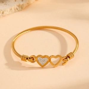 Détail du bracelet double cœur doré avec texture torsadée et diamants incrustés