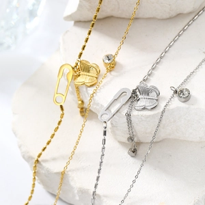 Detail of gold and silver butterfly pendant necklaces with zircon on white stone