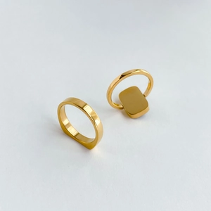 Detail of gold square signet ring and minimalist smooth band set on white background