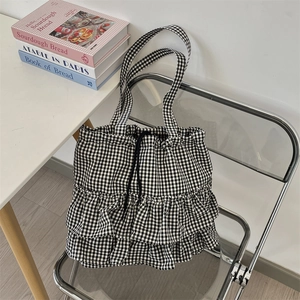 Detail of black and white plaid canvas tote with layered ruffles and drawstring closure