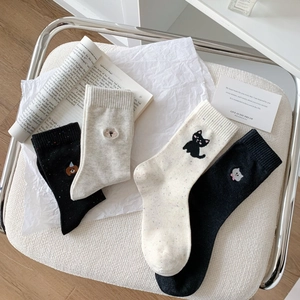 Detail of four pairs of breathable cotton socks with cartoon embroidery on white chair