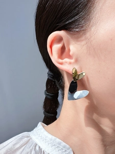 Close-up of heart-shaped earrings in mixed gold and silver tones on a female model