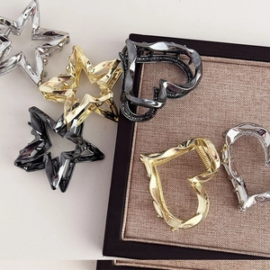 Detail of star and heart metal hair claws with sleek wavy texture in various metallic tones