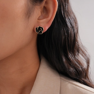 French vintage black rose stud earrings with gold trim worn by a model in a beige suit