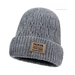 Detailed view of dark grey thick knit beanie featuring a vintage brown leather patch logo