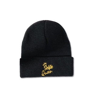 Close-up of yellow Selfie Queen crown embroidery on a black knit beanie hat