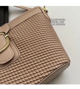 Detail showing the quilted soft fabric texture and gold U-shaped buckle on the nude handbag