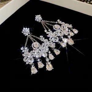 Boucles d'oreilles fleurs argentées avec glands scintillants et cristaux sur fond noir