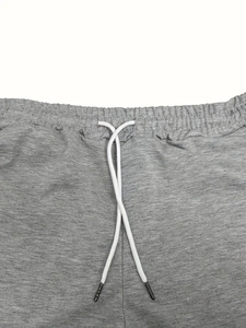 Detail of grey athletic shorts featuring an elastic waistband and white drawstrings