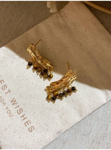 Gold resin tassel earrings with tiger eye beads placed on a natural linen gift bag