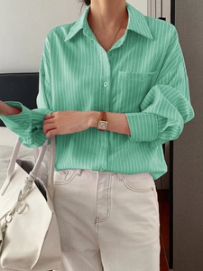 Detail of green striped casual long sleeve shirt showing button closure and fabric texture