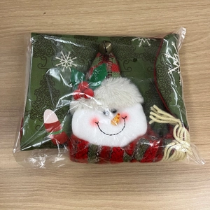 Detail view of a green Christmas stocking featuring a plush snowman doll on wooden background