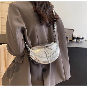 Macro detail of silver crescent saddle bag with metallic chain and dual ring zippers