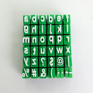 Close-up of green alphabet and symbol stamps for DIY journaling on white background
