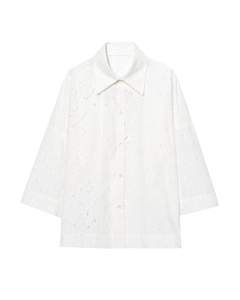 Détail d'une chemise blanche à manches longues montrant le tissu texturé en relief