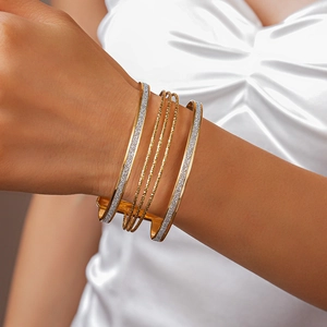Detail of layered gold circles and silver shimmering textured cuffs on person wrist