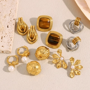 Flat lay of vintage 18K gold plated earrings with pearls and black stones on stone background
