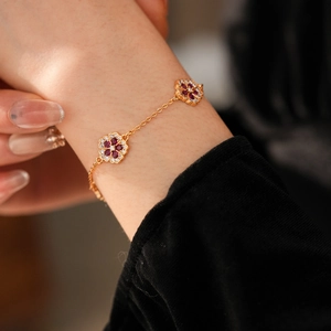 Close-up of 18k gold plated flower bracelet with red and white zircons on wrist