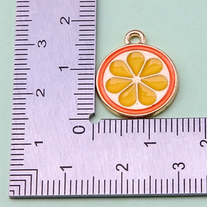 Detail view of mini fruit pendant orange slice charm on scale for size reference