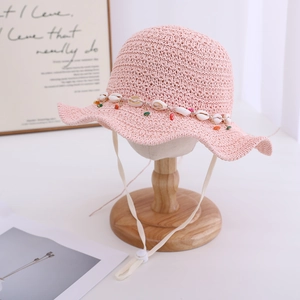 Detail of pink straw sun hat for girls with seashell beads and adjustable chin strap
