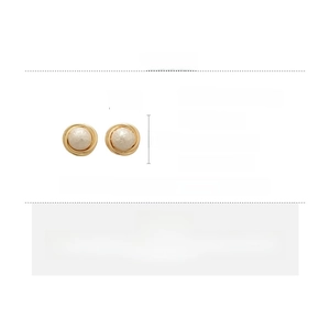 Detail view of geometric gold alloy earrings with textured white cotton pearls