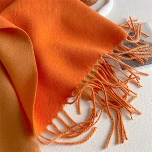 Detailed shot of soft orange gradient cashmere scarf with fringe edges and fine texture