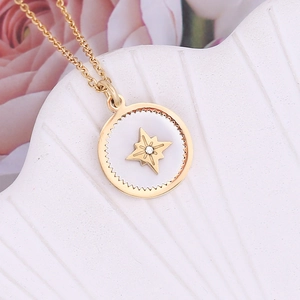 Close-up of gold irregular geometric pendant with starburst and gemstone on shell