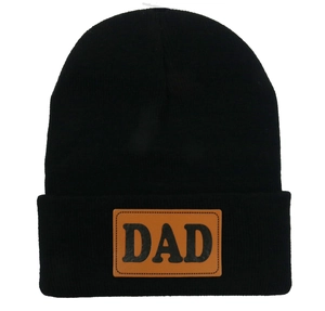 Gros plan d'un bonnet noir en maille avec un écusson en cuir marron marqué DAD