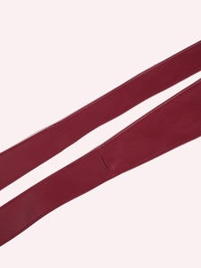 Detailed close-up of wine red faux leather belt with fine stitching and lychee texture
