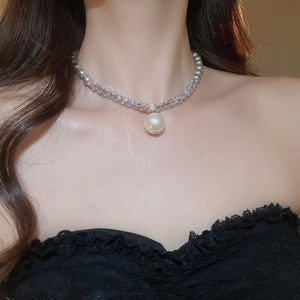 Close-up of grey pearl and crystal pendant necklace worn on neck with lace outfit