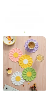 Daisy shaped silicone heat resistant pads in five pastel colors on a wooden table