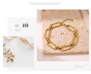 Detailed macro view of gold link chain bracelet with lobster clasp and round logo tag