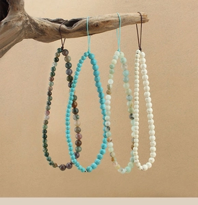 Detail of four colorful turquoise and agate phone wrist straps hanging on a wooden branch