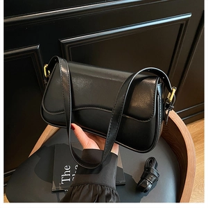 Macro shot showing sleek black leather texture and gold metal buckle of the shoulder bag