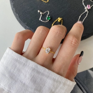 Close-up of a gold chain ring with an oval cubic zirconia stone on a model's hand