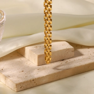 Détail d'une chaîne en acier inoxydable plaqué or 18K sur pierre et soie blanche