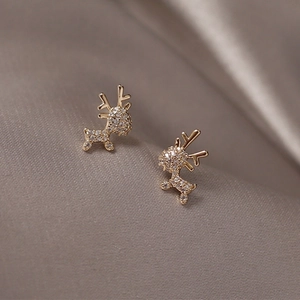 Minimalist gold reindeer earrings with sparkling crystals on silk background