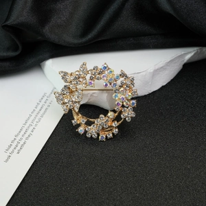 Elegant gold wreath brooch with colorful crystals on a minimalist stone setting
