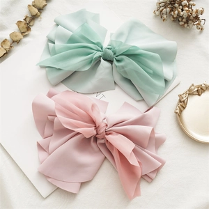 Detail of mint green and dusty pink fabric bow hair clips with tulle layers on book