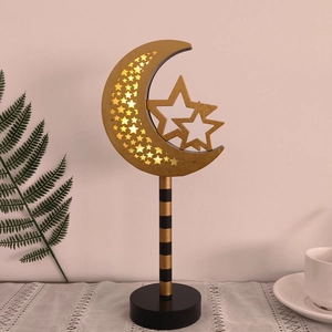 Detailed view of a golden moon and star LED ornament on a black minimalist pedestal