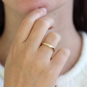 Close-up of polished gold-plated stainless steel band ring on a hand for a minimalist look