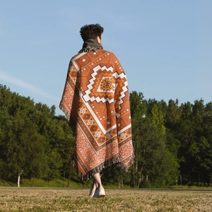 Detailed Bohemian geometric jacquard pattern on a heavy knit blanket with long fringes