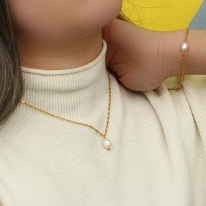 Elegante set di gioielli dorati con perle d'acqua dolce bianche indossato da una modella