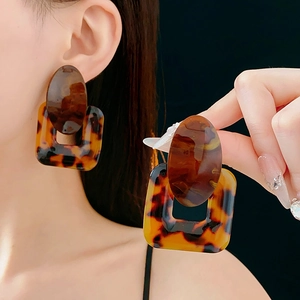 Close-up of a model wearing large square tortoiseshell resin earrings in a retro style