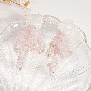 Detail of pink crystal stone drop earrings on a pearlescent shell tray with dried flowers