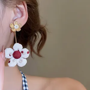 Floral drop earrings with red polka dot fabric flower and pearl accents on model